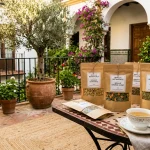 Sunlit Spanish courtyard terrace in Seville with organic herbal botanical pouches and tea (AI Generated Image)